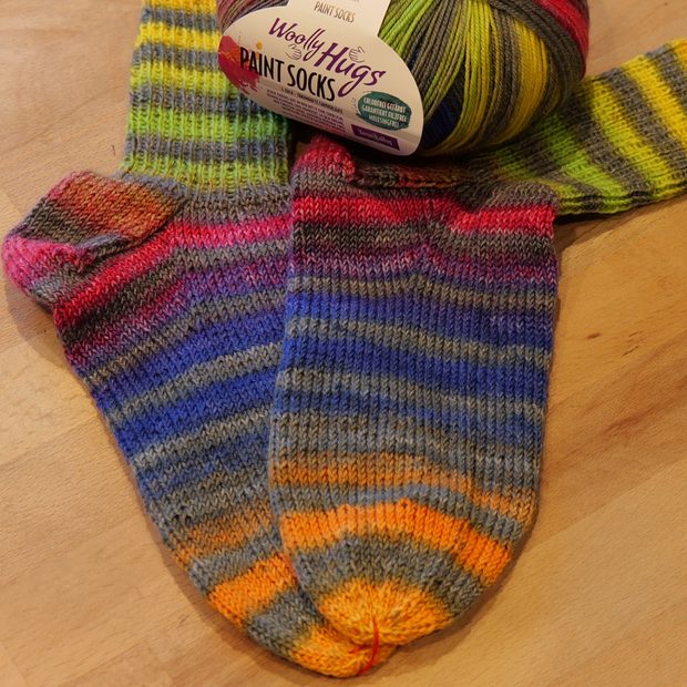 Gestrickte Socken aus Farbverlaufsgarn mit dem Knäuel daneben